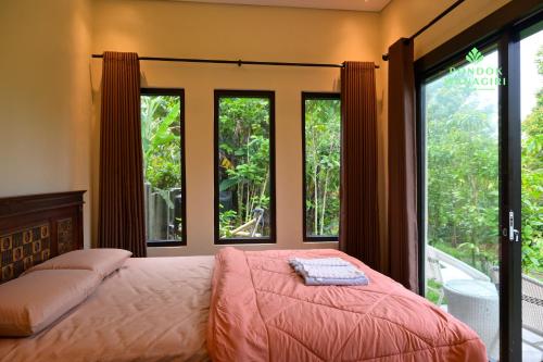 a bedroom with a bed and large windows at Pondok Wanagiri in Gitgit