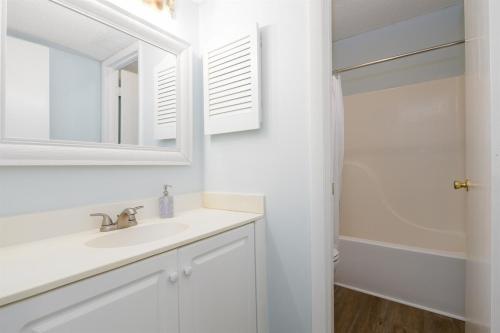 a white bathroom with a sink and a mirror at Coast is Clear- Oceanfront Escape at Topsail Dunes in North Topsail Beach