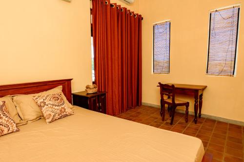a bedroom with a bed and a desk and windows at Villa302 in Galle