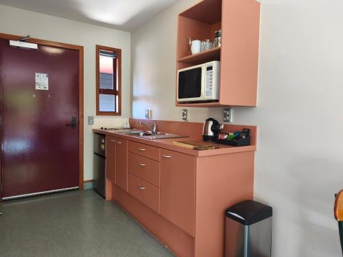 a small kitchen with a sink and a microwave at Aspen Lodge Motel in Hanmer Springs