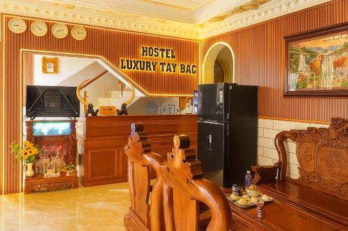 a room with a wooden chair with a sign that reads hostel luxury try bar at Hostel Luxury Tây Bắc in Rạch Giá
