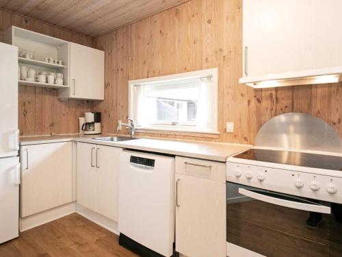 een keuken met witte apparatuur, houten wanden en een raam bij Holiday home with sauna, whirlpool- Type1 in Blåvand