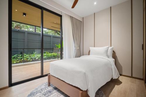 a bedroom with a white bed and a large window at Laguna Beachside Residences Building 2 by Banyan Living in Bang Tao Beach