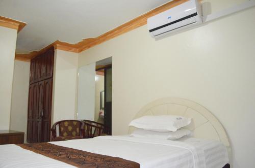 a bedroom with a bed with white sheets and a tv at Mt. Zion Hotel Annex in Kampala
