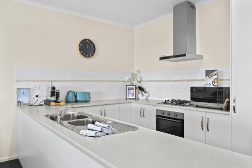 a white kitchen with a sink and a stove at Bayview Escape - Aldinga Beach - C21 SouthCoast Holidays in Aldinga Beach