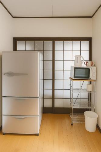a kitchen with a refrigerator and a microwave at Nippori Osaka Nishi-Tengachaya Guesthouse西天下茶屋アパートメント in Osaka