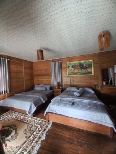 2 Betten in einem Schlafzimmer mit Holzvertäfelung in der Unterkunft Jati mulyo Cottage Dieng in Batur