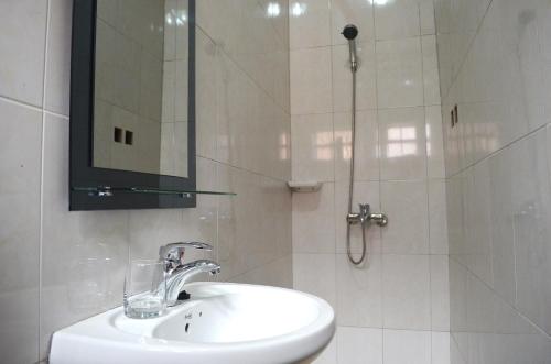 a white bathroom with a sink and a shower at Mt. Zion Hotel Annex in Kampala