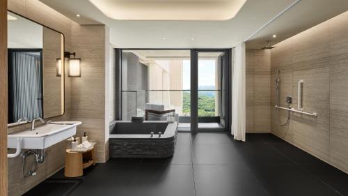 a bathroom with a tub and a sink and a mirror at InterContinental Hotels New Taipei Hot Spring by IHG in Jinshan