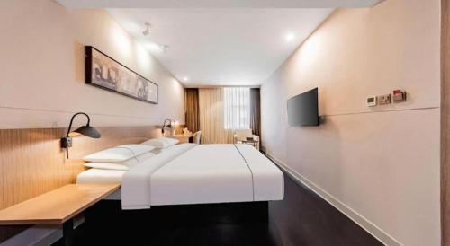 a bedroom with a large white bed and a desk at Jinjiang Inn Select Hohhot Chengjisihan Square Metro Station in Hohhot