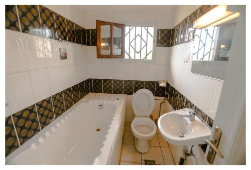 a bathroom with a tub and a toilet and a sink at Résidence Suzanne in Brazzaville