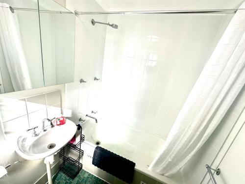ein weißes Badezimmer mit Waschbecken und Dusche in der Unterkunft Modern Crestwood Retreat - 2BR Near Canberra City in Queanbeyan