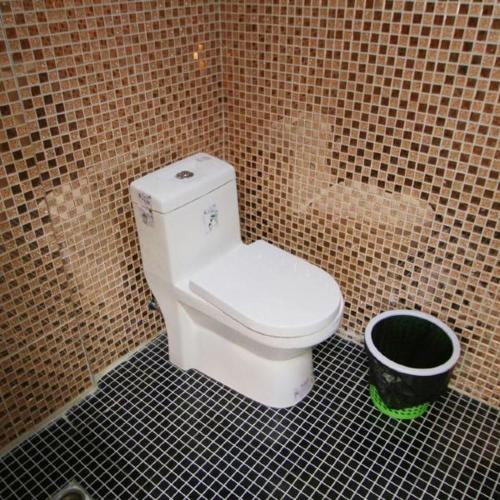 eine Toilette in einem gefliesten Badezimmer mit einem Eimer in der Unterkunft Shanghai Yujia Hotel in Shanghai