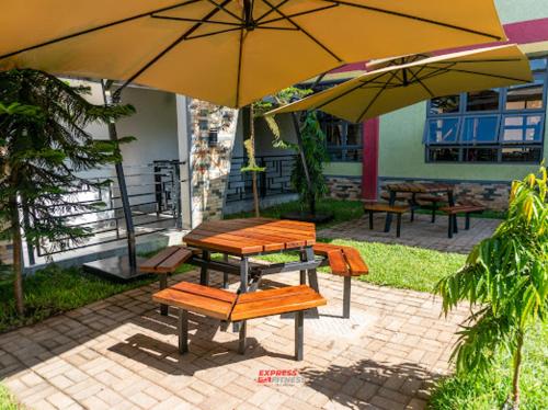 a picnic table and benches under an umbrella at Express living and wellness in Jinja