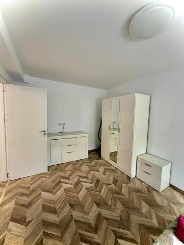 ein leeres Zimmer mit weißen Schränken und Holzboden in der Unterkunft Apartament Draganovi 8 in Kasanlak