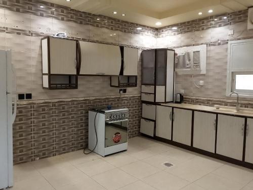 a kitchen with white cabinets and a stove top oven at Al Madinah Hotel in Al Madinah