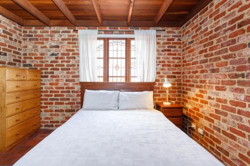 ein Schlafzimmer mit Backsteinwänden, einem Bett und einem Fenster in der Unterkunft Burn Street Loft - North Fremantle in North Fremantle