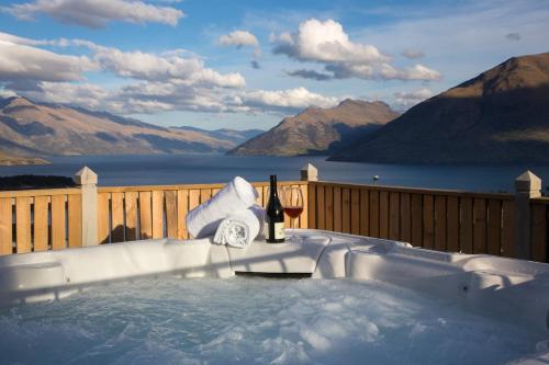 a hot tub with a bottle of wine and a glass at Alpine Luxury on London in Queenstown