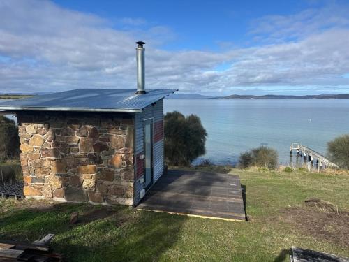 a small stone building with a wooden deck next to the water at Absolute waterfront with a secret garden in Carlton