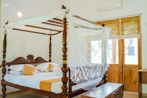 a bedroom with a canopy bed with white sheets at Rivendell Twisted Tree in Kurunegala