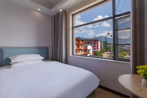 a bedroom with a bed and a large window at Hua Han Hotel in Zhangjiajie