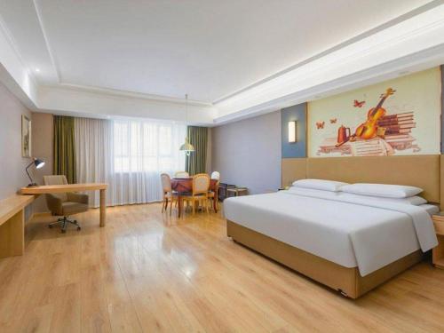 a hotel room with a bed and a table and chairs at Vienna Hotel Xuzhou Junsheng Plaza Benteng Avenue Metro Station in Xuzhou