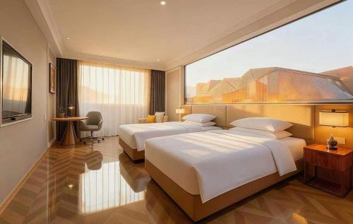a hotel room with two beds and a television at Vienna Hotel Jiangsu Dongtai Wanghai West Road in Dongtai