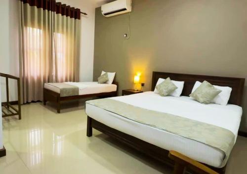 a bedroom with two beds and a window at Osara Holiday Home in Anuradhapura