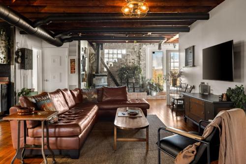 a living room with a leather couch and a table at Unique 2-BDR Historic Warehouse Loft with Terrace ! ! ! in Windsor