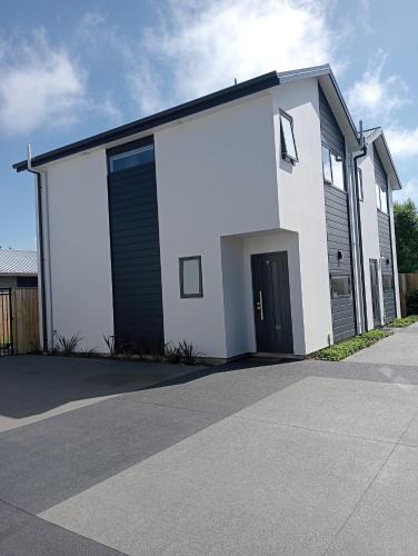a white house with a black door and a driveway at Frederick Street Town house in Christchurch