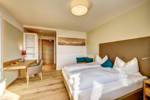a bedroom with a large bed and a desk at Garni Hotel Kessler in Tirolo