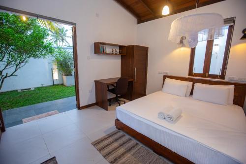 a bedroom with a bed and a desk and a window at Villa D8 in Mirissa