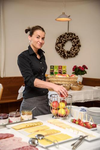 a woman standing behind a table with a bowl of fruit at Garni Hotel Kessler in Tirolo