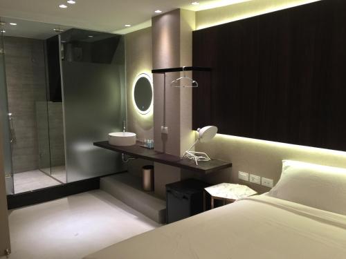 1 dormitorio con 1 cama y baño con ducha en Kenting Feliz Hotel, en Kenting