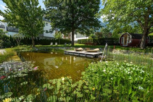 a pond with a boat in the middle of a yard at Garni Hotel Kessler in Tirolo