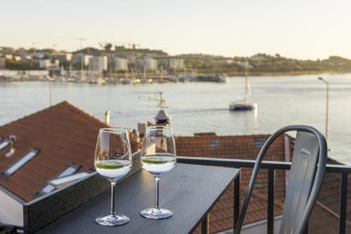 two wine glasses sitting on a table with a view of the water at D&S - Foz Riverside Apartment in Porto