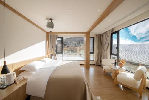 a bedroom with a white bed and a large window at Yunlanli Mountainside Homestay in Shangri-La