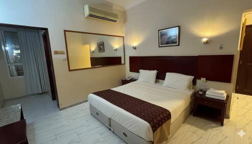 una habitación de hotel con una cama y un espejo en Makran Palace Hotel, en Ma‘ābīlah