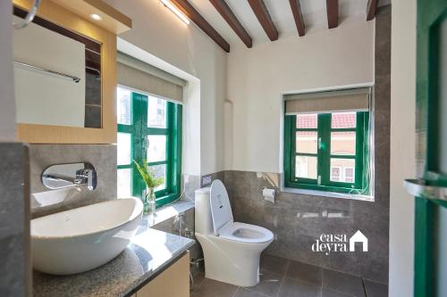 ein Badezimmer mit einem Waschbecken und einem WC sowie zwei Fenster in der Unterkunft Hajuri Kunj Bungalow in Kathmandu