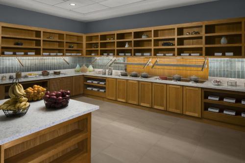 a large kitchen with wooden cabinets and fruit on the counter at Hyatt Place Denver Cherry Creek in Denver