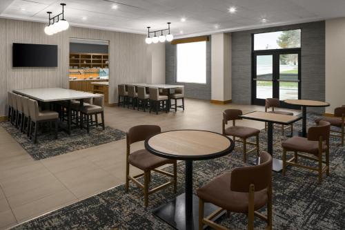 a waiting room with tables and chairs and a tv at Hyatt Place Denver Cherry Creek in Denver