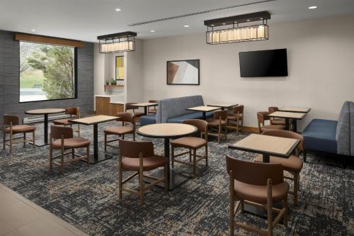a waiting room with tables and chairs and a flat screen tv at Hyatt Place Denver Cherry Creek in Denver