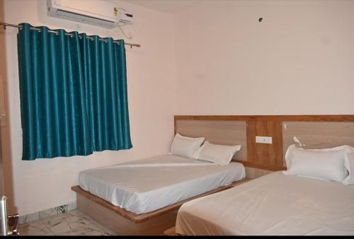 two beds in a room with a green curtain at Malwa resort in Chitrakoot