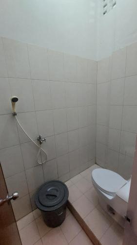 a bathroom with a toilet with a black seat at Gedung Putih Syariah in Palas 2