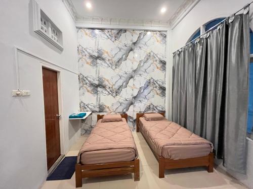 een kamer met 2 bedden en een muurschildering bij Gedung Putih Syariah in Palas 2