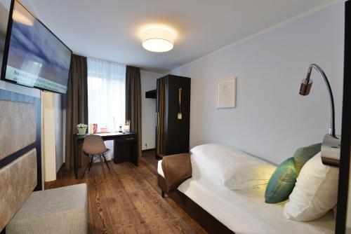 a hotel room with a bed and a desk at UHU Gästehaus Superior in Cologne
