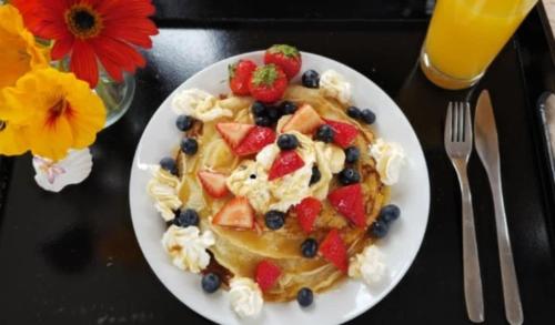 a white plate of food with fruit on a table at Perrys South by Tiny Away in Forth