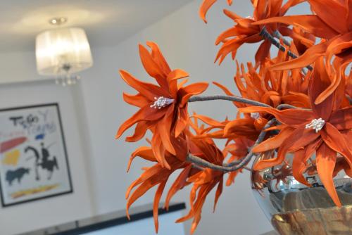 a vase filled with orange flowers in a room at UHU Gästehaus Superior in Cologne