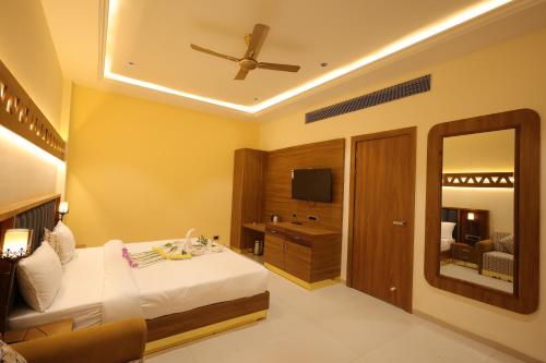 een hotelkamer met een bed en een spiegel bij Ramaya Motel & Resort, Ujjain in Ujjain