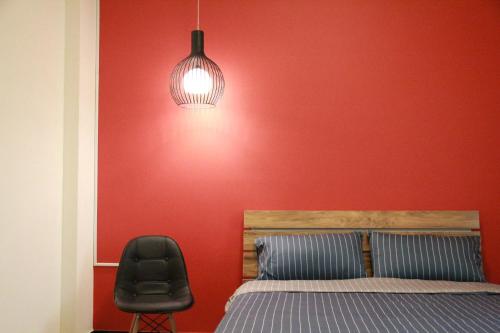 a bedroom with a red wall with a bed and a chair at Little Weekend Inn in Jincheng